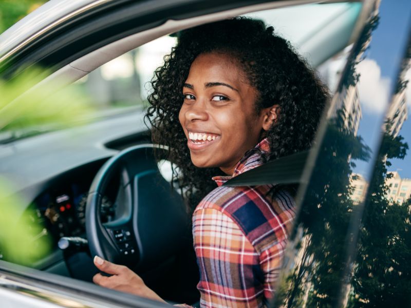 Happy driver sitting safely in their car equipped with a personal GPS tracker